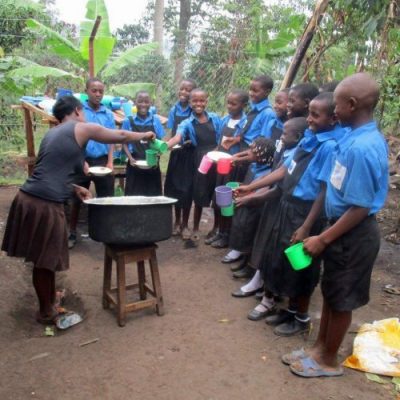 school cook handing out breakfast to pupils at uphill junior school in uganda