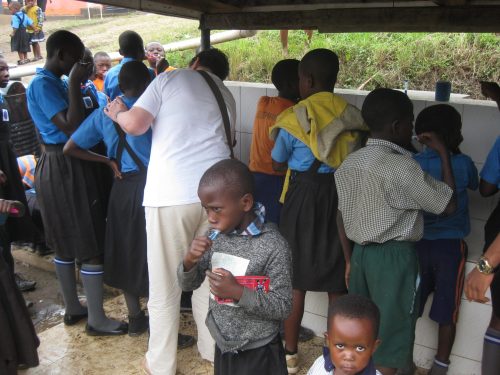 helping ugandan pupils to brush their teeth correctly in a rural school