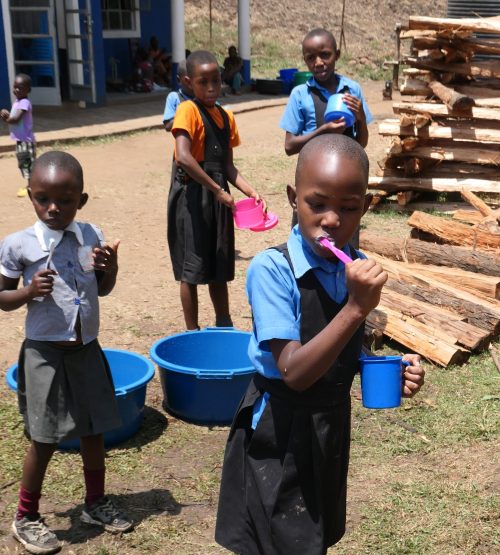 ugandan pupils brushing their teeth in a rural primary school