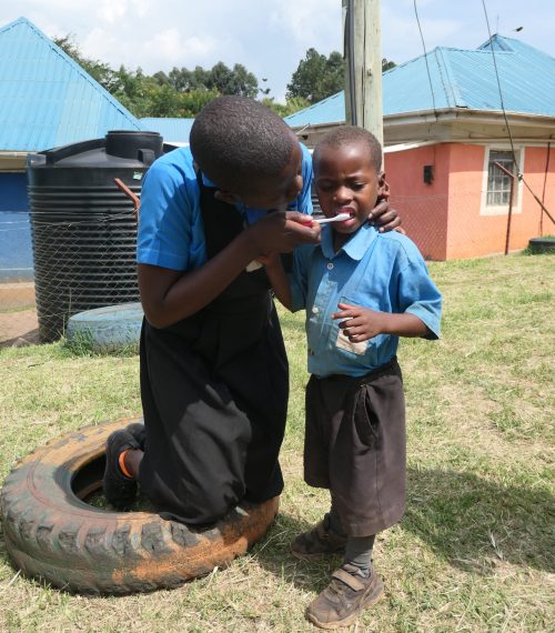 girl helping young boy to brush his teeth